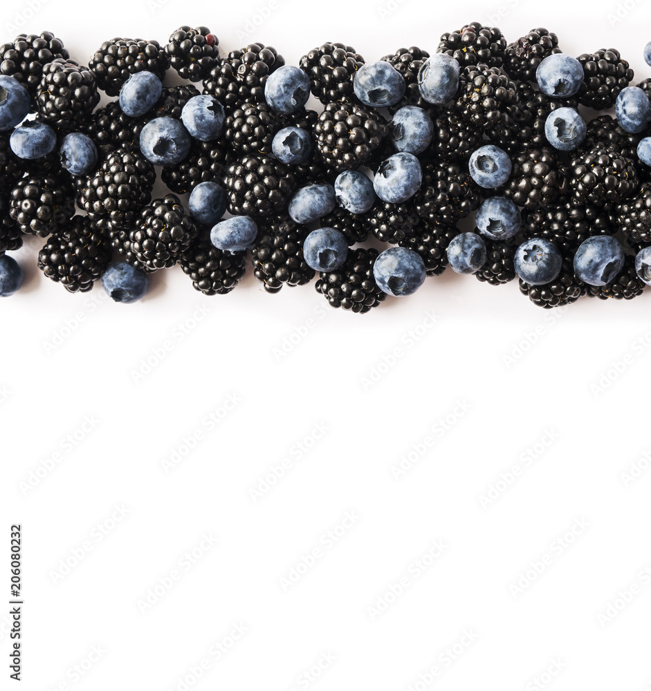 Top view. Ripe blackberries and blueberries on white background. Berries at border of image with copy space for text. Top view. Ripe blackberries and blueberries on white background. Berries at border of image with copy space for text.