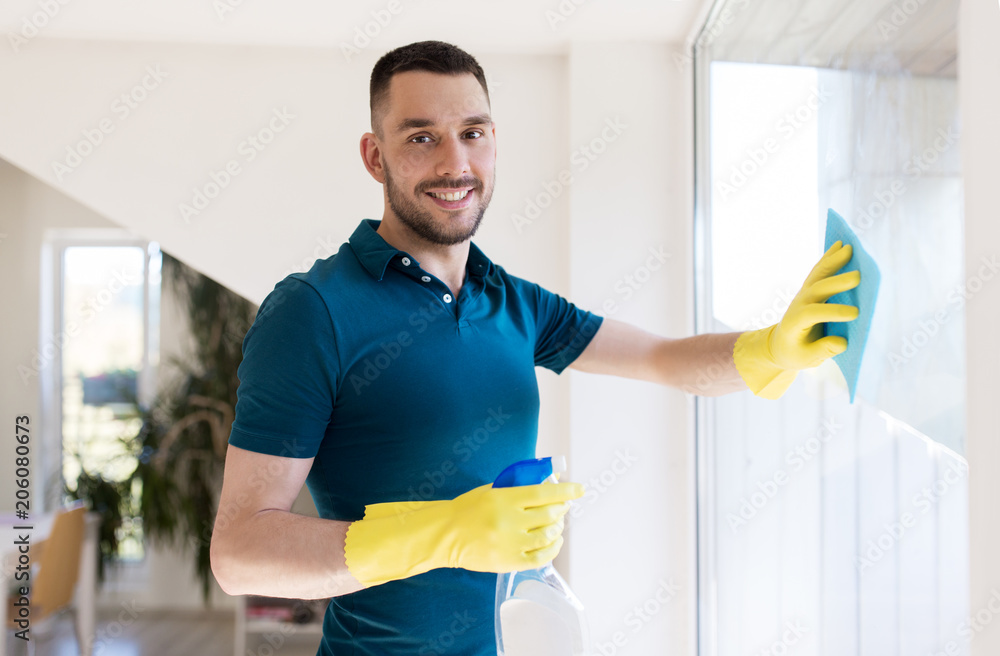 Photography household and people concept - man in rubber gloves cleaning window with rag and