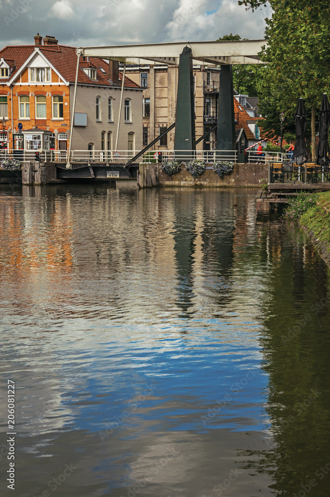 Clouds and sky reflected in canal water surface, buildings and bascule bridge on a sunny day in Weesp. Quiet and pleasant village full of canals and green near Amsterdam. Northern Netherlands.