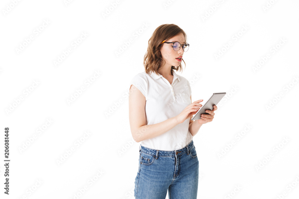 Portrait of beautiful lady in eyeglasses standing and thoughtfully working on the tablet on white background isolated Portrait of beautiful lady in eyeglasses standing and thoughtfully working on the tablet on white background isolated