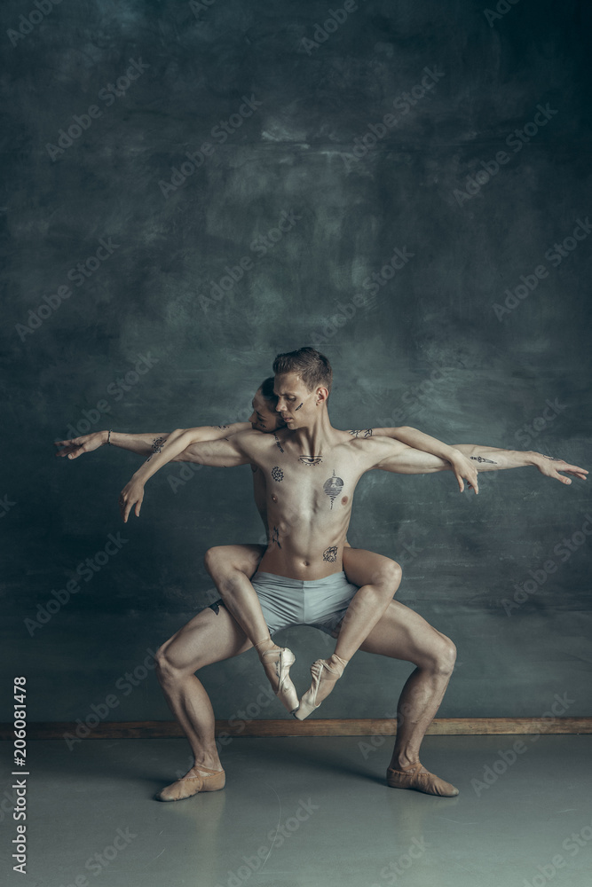 The young modern ballet dancers posing on gray studio background The young modern ballet dancers posing on gray studio background