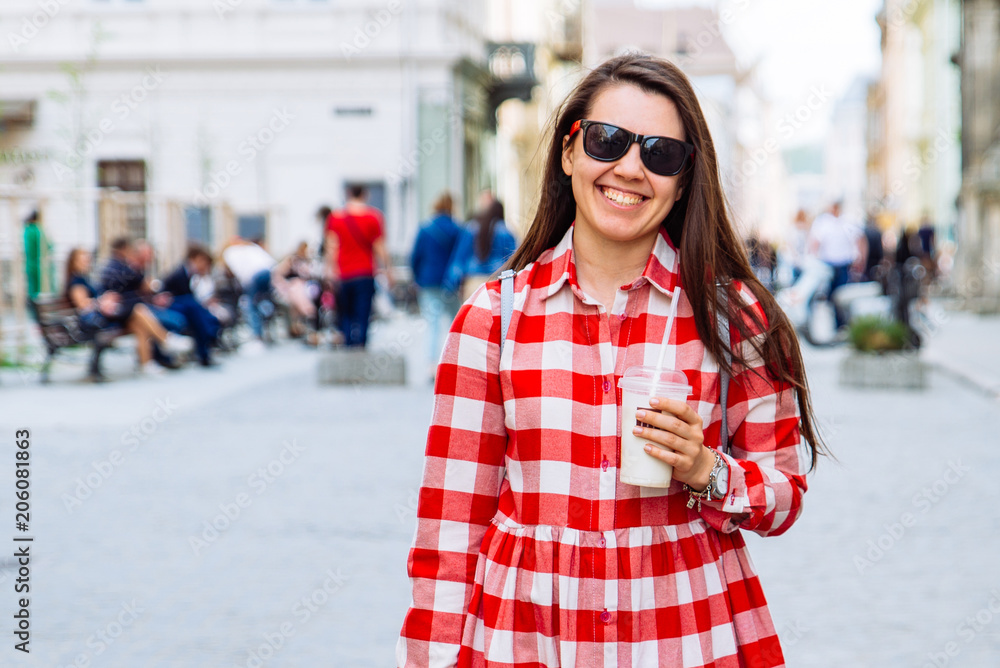 woman drinking cool drink while walking city street at summer day woman drinking cool drink while walking city street at summer day