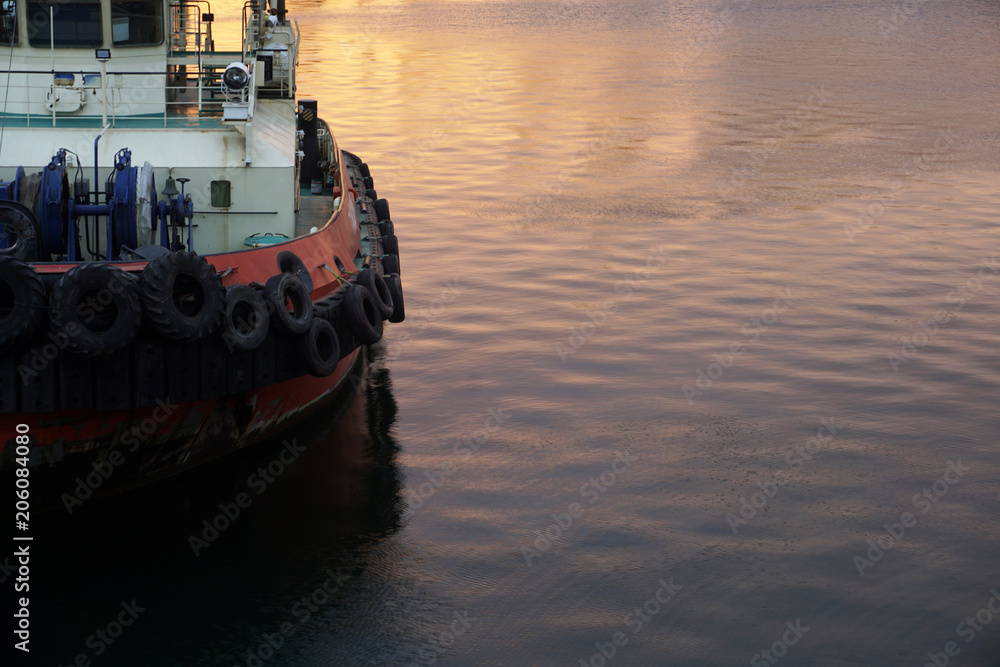Tugboat on sea in the rays of the setting sun.