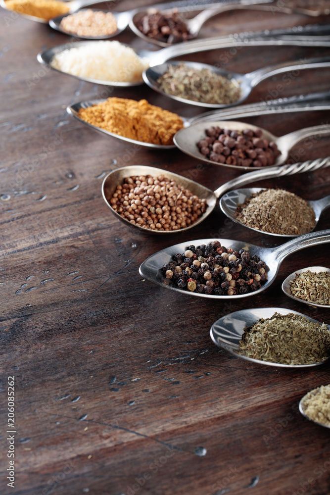 Different spices in spoons on a wooden background. Different spices in spoons on a wooden background.