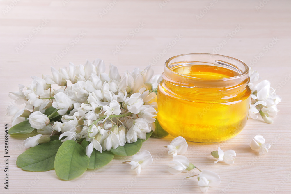 Acacia honey in a glass jar on a natural wooden background Acacia honey in a glass jar on a natural wooden background