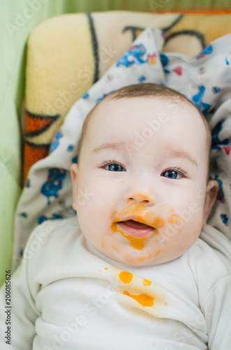 baby with blue eyes eats pumpkin puree