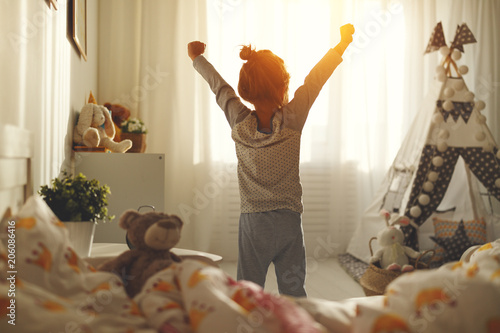 child girl wakes up  and stretches in morning in bed and stretches photo