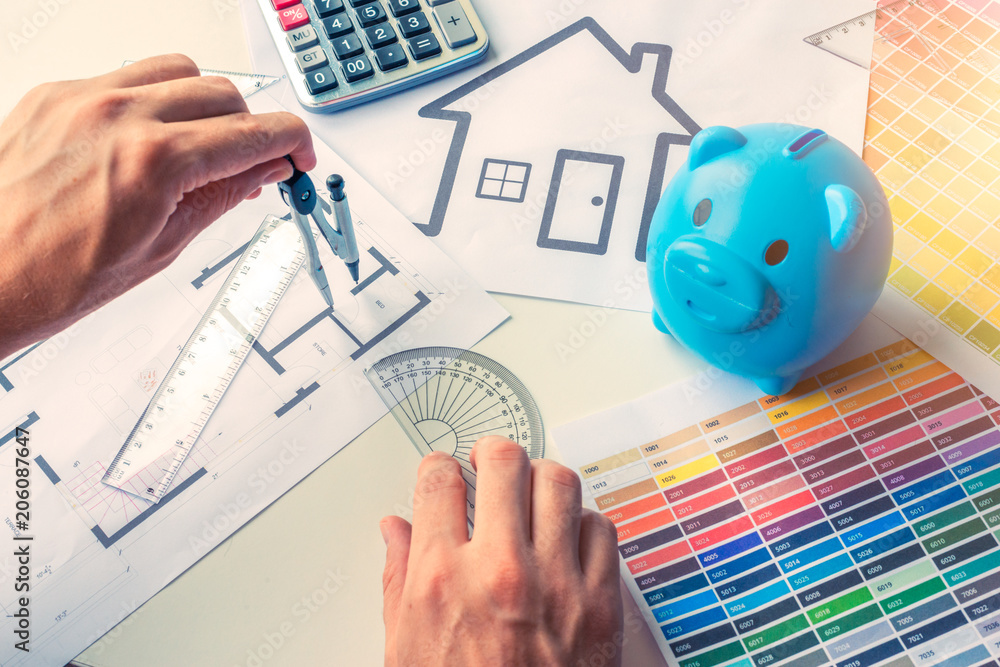 Architect drawing plan of house with colors chart, piggy bank and calculator Architect drawing plan of house with colors chart, piggy bank and calculator