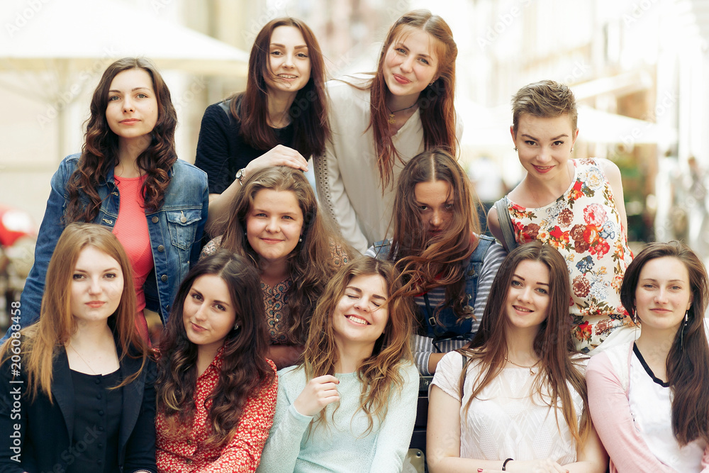 stylish women hipster smiling and sitting on bench in europe city street, joyful moments friendship concept