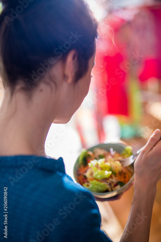 A young woman eating a salad in a bowl