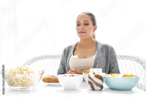 Many sweets. Pensive musing woman posing at table and looking at food
