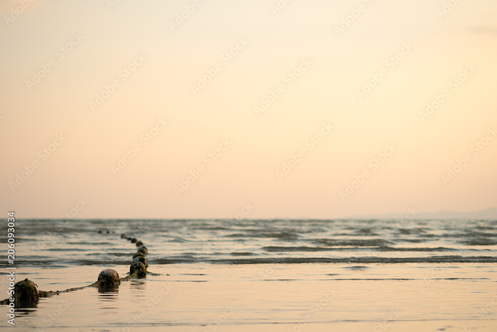 Sunset sea and beach with floating rope in evening.