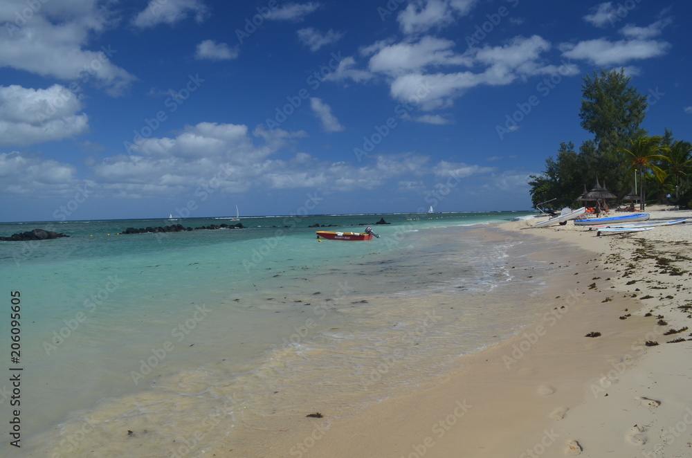 Turquoise water and a white sandy beach with a blue sky and a red boat