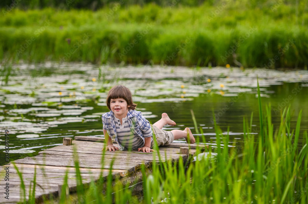 the boy lies on a wooden bridge overgrown river the boy lies on a wooden bridge overgrown river
