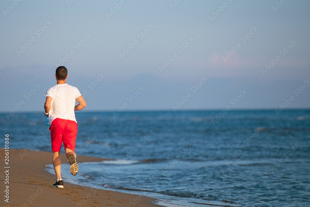 Man running on the beach at sunset