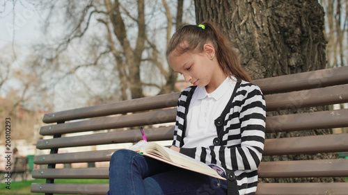 outdoor park education. leisure time. Young cute teen sitting bench reading book.