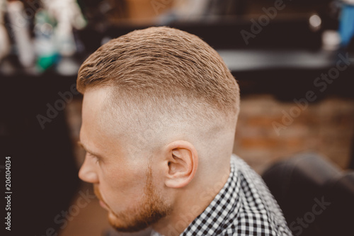 Man in barber chair, hairdresser styling in barbershop. close-up for parting and transition