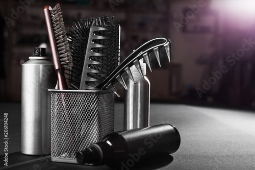 three flacons of professional hair sprays near a basket with hairbrushes standing on a table in a salon. concept of hair caring tools. free space for advertising