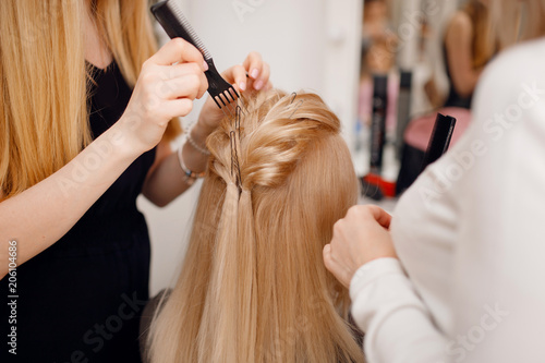 Hairdresser does hairstyle for woman to weave braids, styling. Concept wedding specialist, workshop, training.
