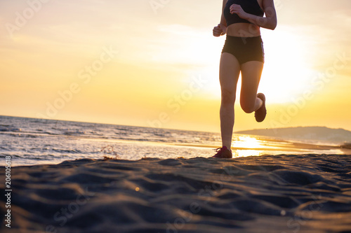 Healthy young fitness woman runner running on sunrise seaside trail
