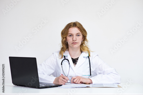 Portrait of a beautiful blonde doctor girl on white background with a laptop