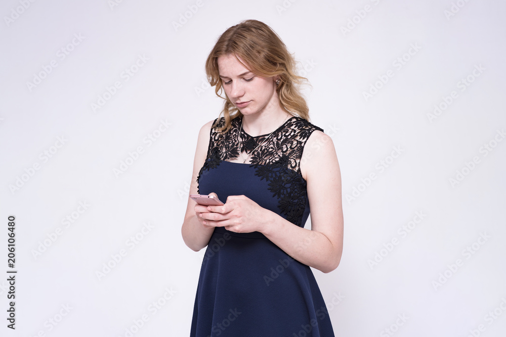 Portrait of a beautiful young blonde girl on a white background listening to music in headphones with a smartphone Portrait of a beautiful young blonde girl on a white background listening to music in headphones with a smartphone