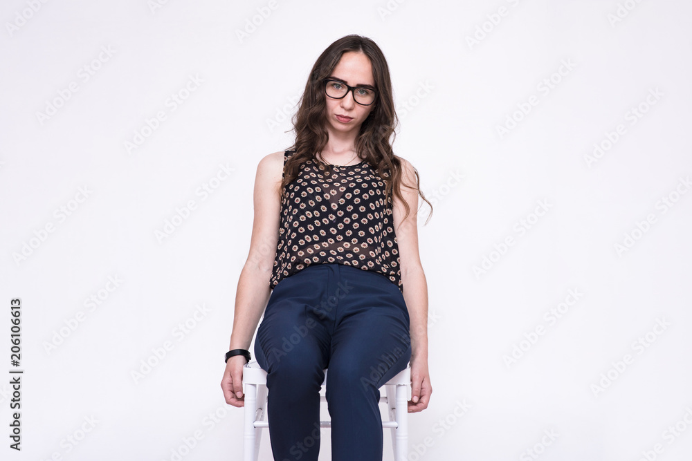 portrait of a young beautiful brunette girl on a white background sitting on a chair.