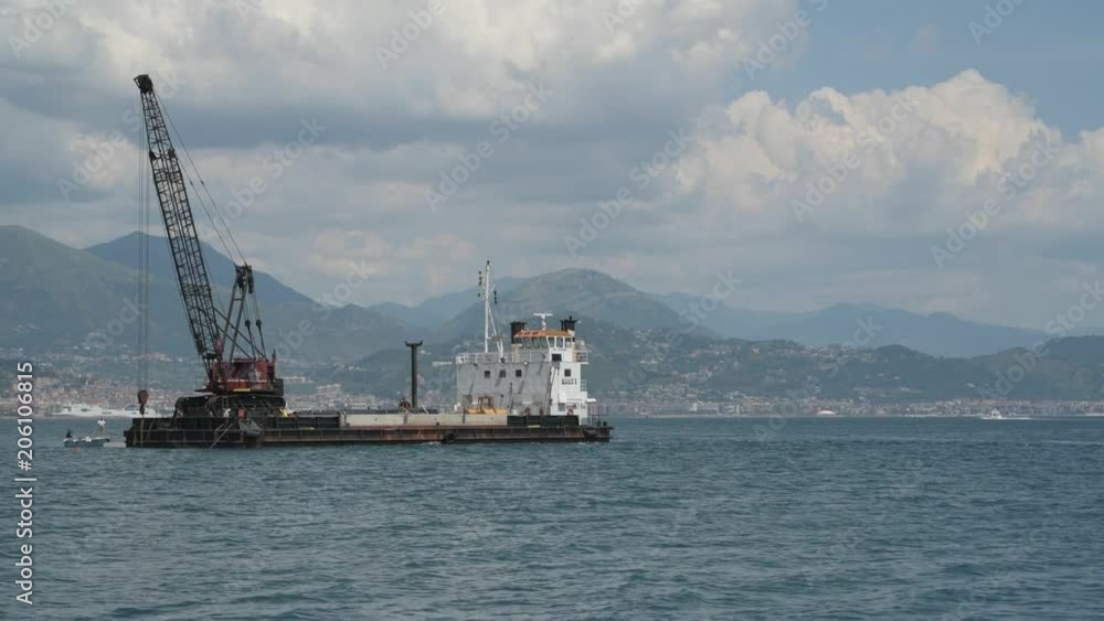 Barge doing some maintenance in the middle of the sea using a tower crane Barge doing some maintenance in the middle of the sea using a tower crane