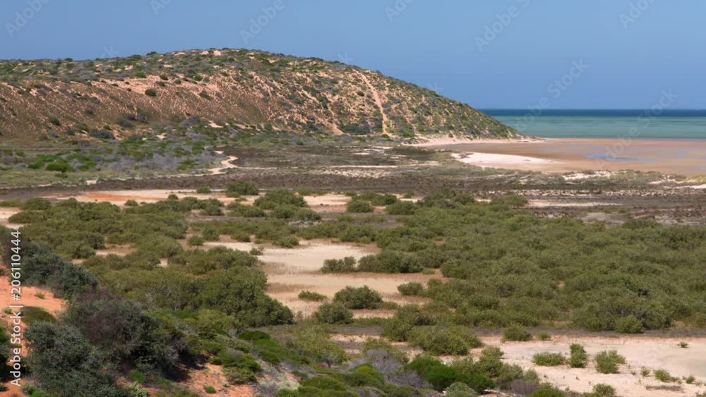A wide shot of a beach and cliff with the ocean.