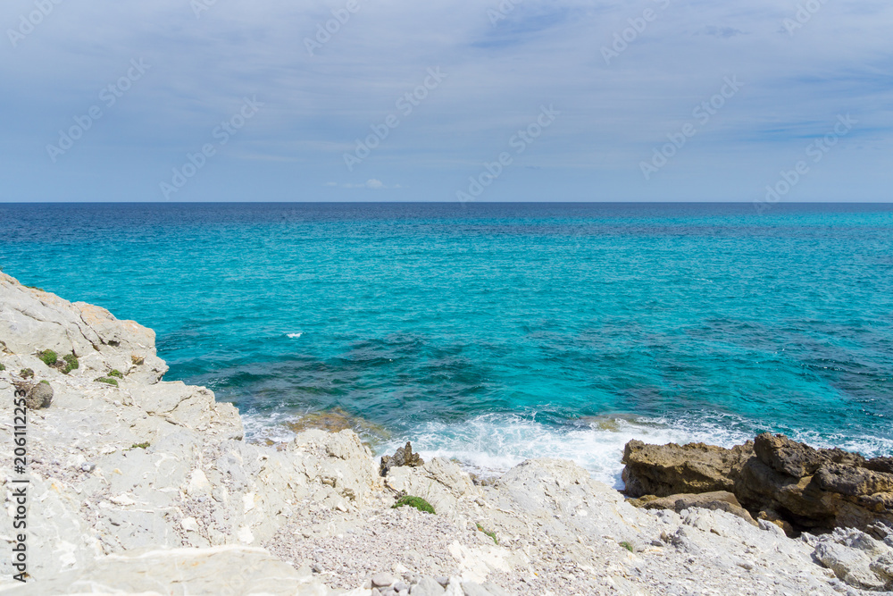 Mallorca, Endless blue horizon of clear sea water at white chalk rock coast with sun