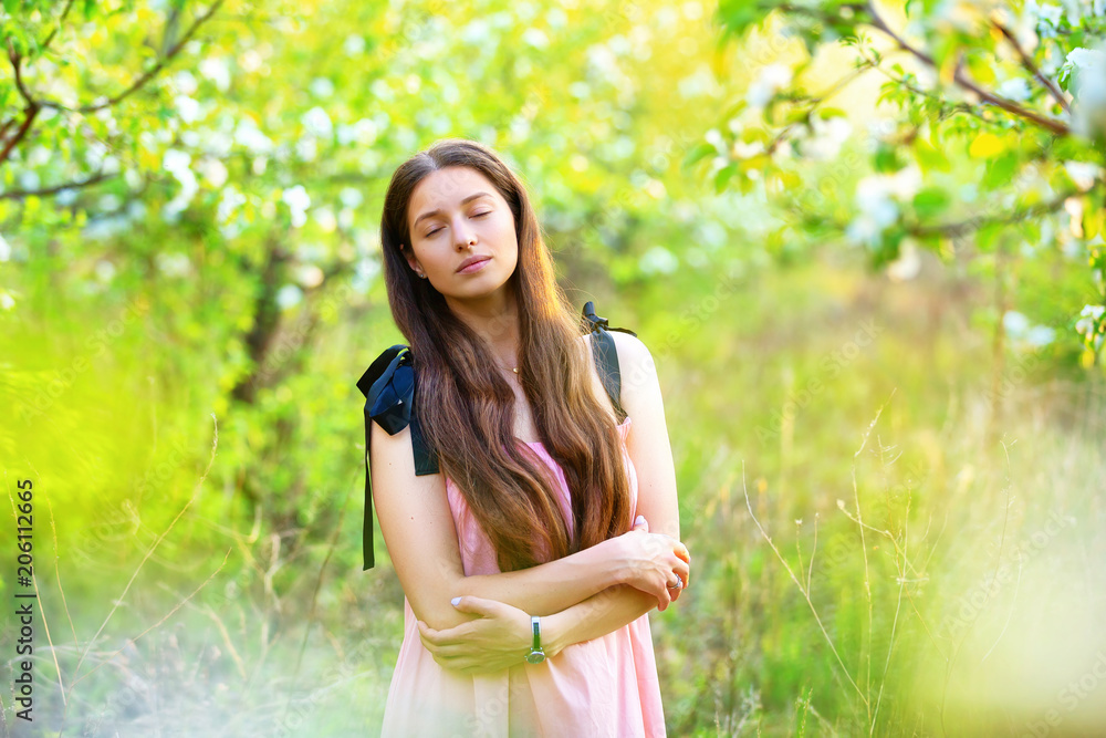 Portrait of young girl with closed eyes dreaming at blooming spring garden background. oncept of happiness.