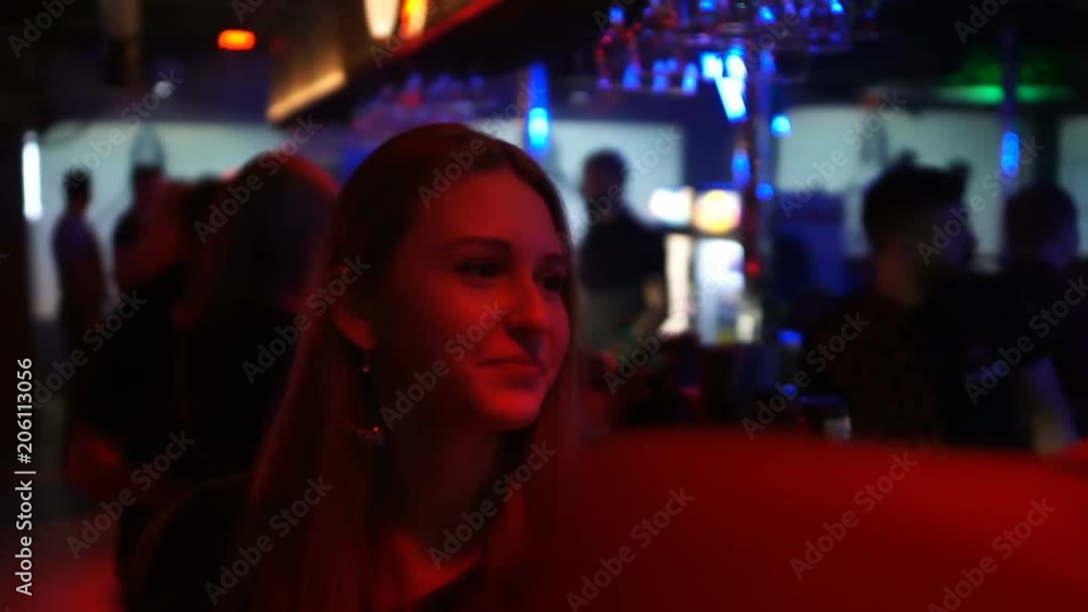 Pretty girl talking with male and smiling, relaxing near bar counter at club Pretty girl talking with male and smiling, relaxing near bar counter at club