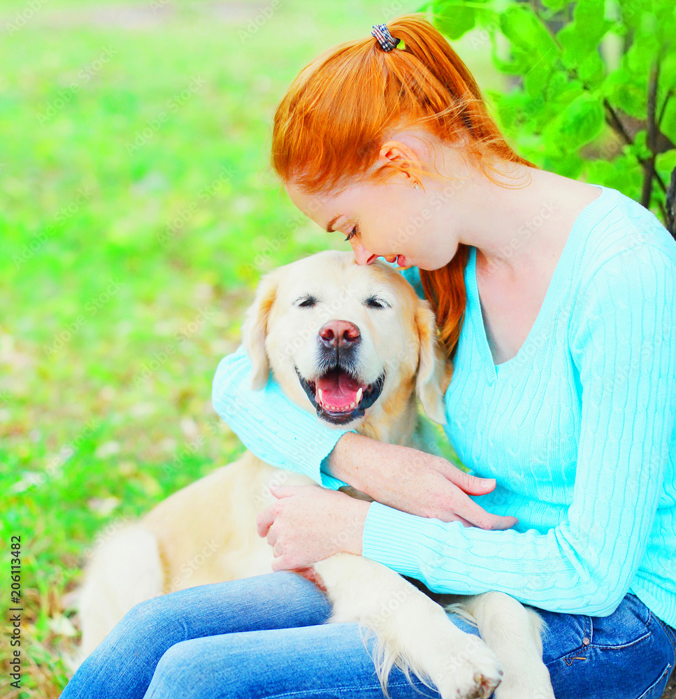 Owner woman is hugging her Golden Retriever dog on the gra Owner woman is hugging her Golden Retriever dog on the gra