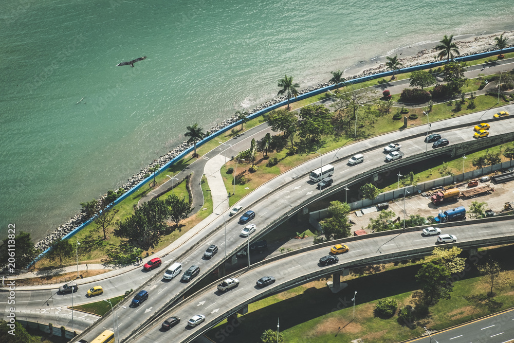 Cars driving on highway near ocean coast - city traffic aerial