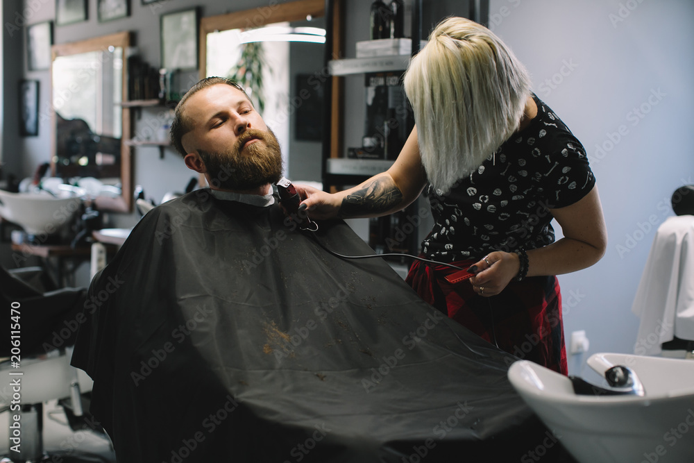 Getting perfect shape. Close-up side view of young bearded man getting beard haircut by hairdresser at barbershop Getting perfect shape. Close-up side view of young bearded man getting beard haircut by hairdresser at barbershop
