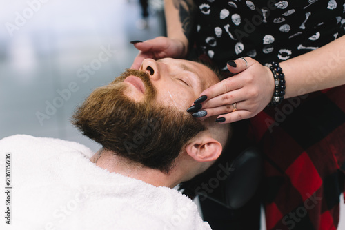Handsome bearded man, hipster, brunette with beard and moustache has shave in barbershop.