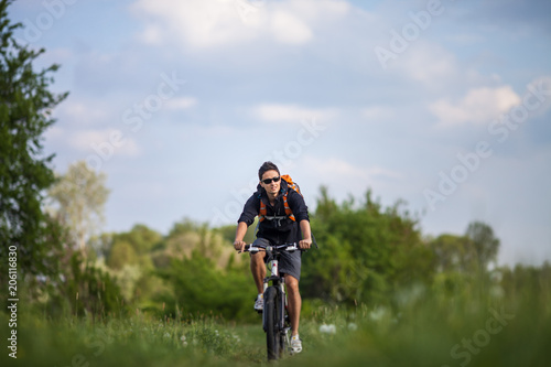 Handsome young man biking in the countryside