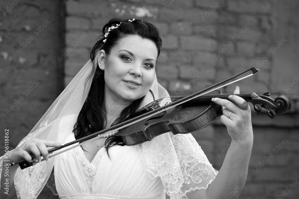 Beautiful bride in white dress playing violin melody,black white