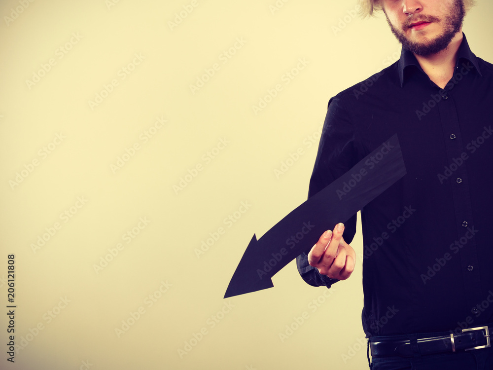 Man holding black arrow pointing left down Man holding black arrow pointing left down
