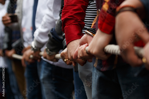 Various people pulling rope together, closeup of hands. Teamwork. Unity concept. Selective focus