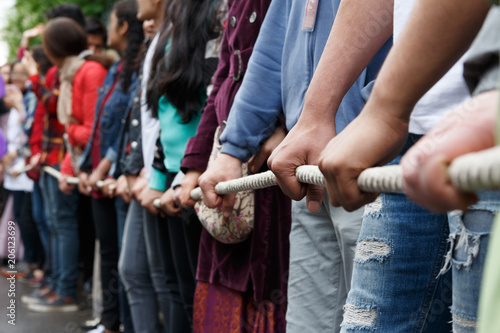 Various people pulling rope together, closeup of hands. Teamwork. Unity concept. Selective focus