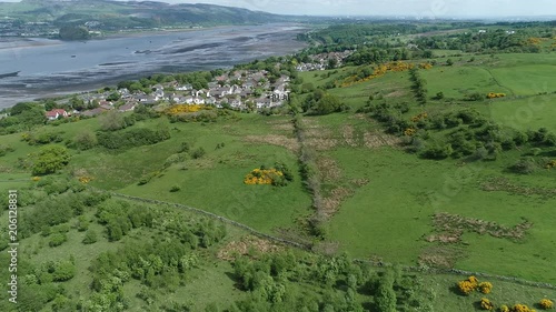 Aerial footage flying over woodland and yellow gorse covered hillside to the village of Langbank on the south shore of the Firth of Clyde. photo