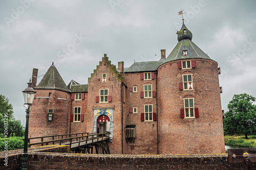 Medieval Ammersoyen Castle with its brick towers  wooden bridge and green garden on cloudy day. Near to the historic and vibrant city of s-Hertogenbosch. Southern Netherlands