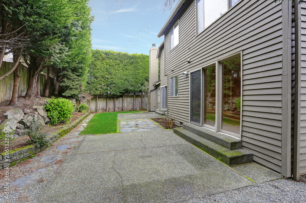 Private yard of a grey house with green grass.