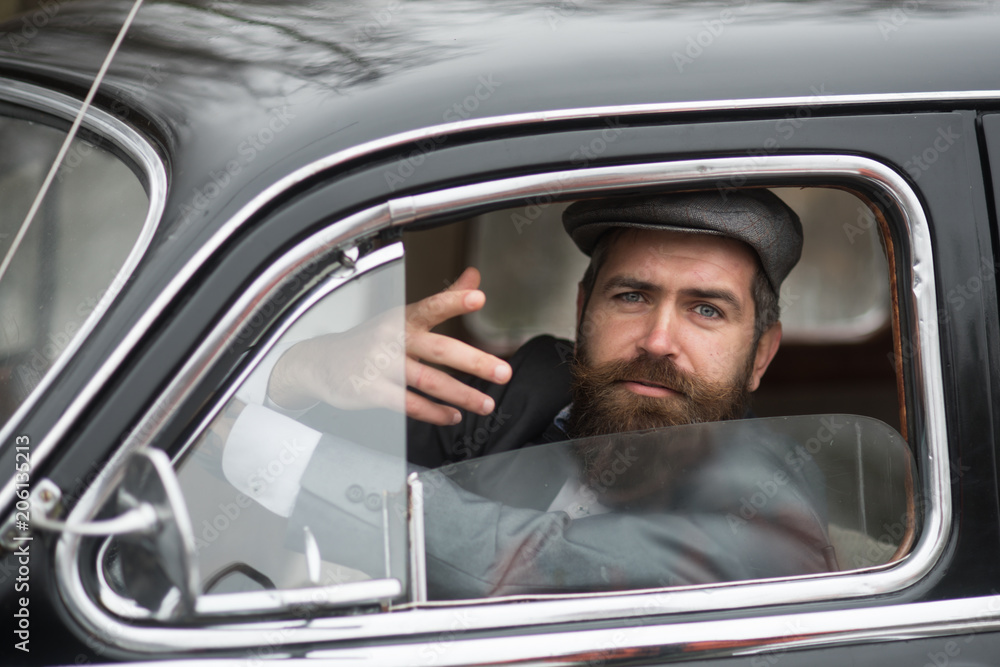 Retro man in retro car showing communicative gesture.