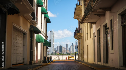 A colorful alley on a sunny day in the old town Casco Viejo with the skyline of Panama City in the background.