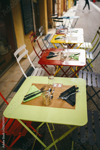 Theme cafes and restaurants. Exterior summer terrace of bright colors of street cafe shop in Europe in France. Preserved tables Without people, at tables nobody