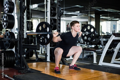Newbie bodybuilder in black sportswear lifting heavy weight in gym