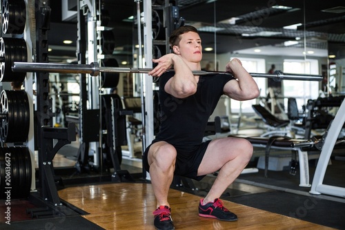 Bodybuilder in black sportswear lifting heavy weight in the gym