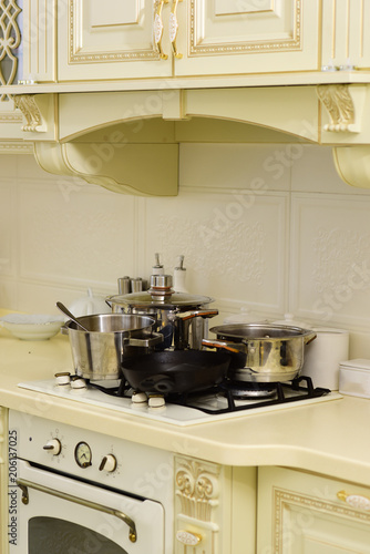 Stove with pots and pans on countertop. Stove with cooking utensils on white wall tile. Kitchen appliance and furniture. Kitchen design in vintage style. Cooking at home concept